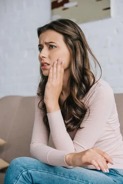 woman experiencing jaw pain due to TMJ disorder